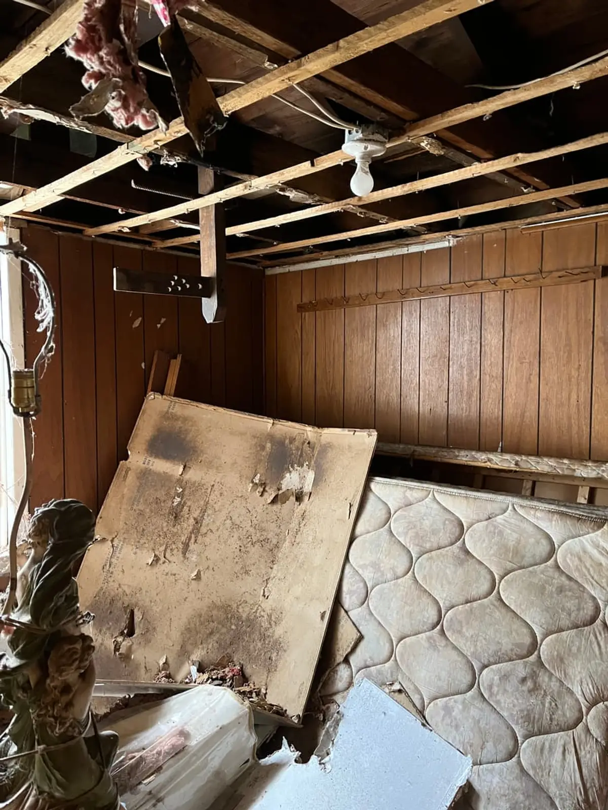 Selling a water-damaged house in Brentwood: collapsed ceiling hanging over a mattress