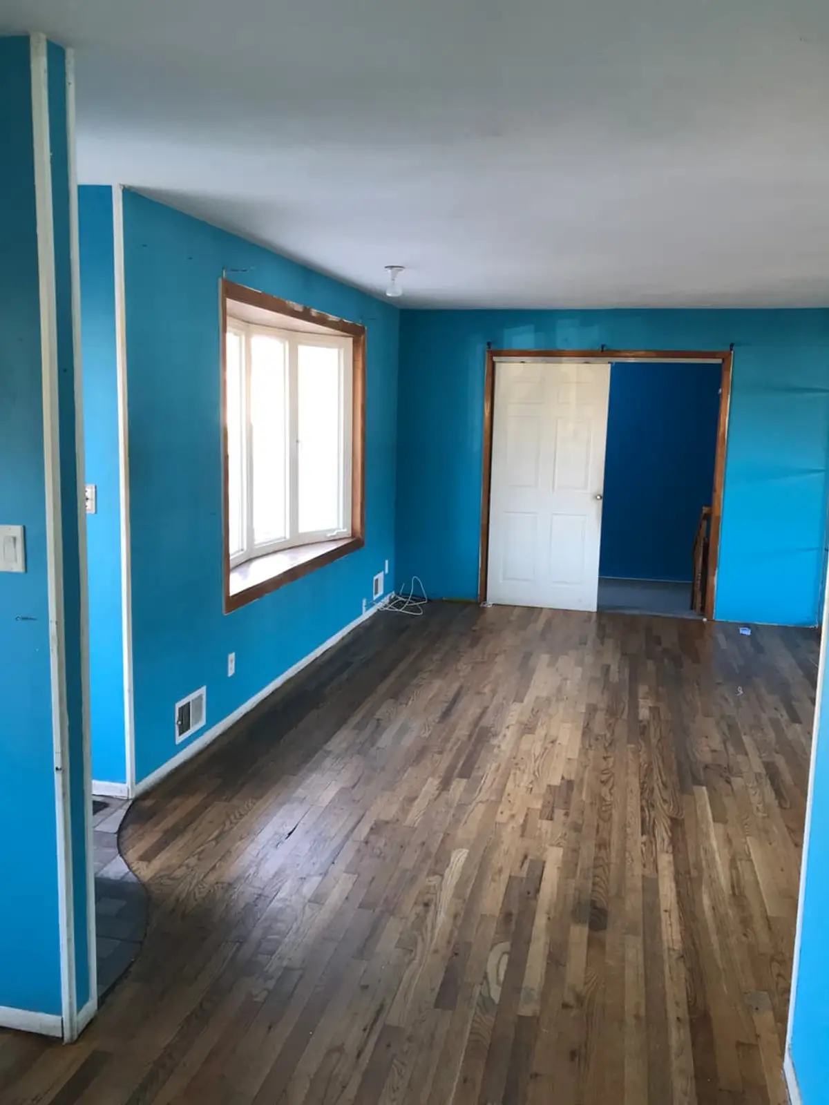 Selling a house with back taxes in Brentwood: empty living room with bright blue walls and a dark wood floor