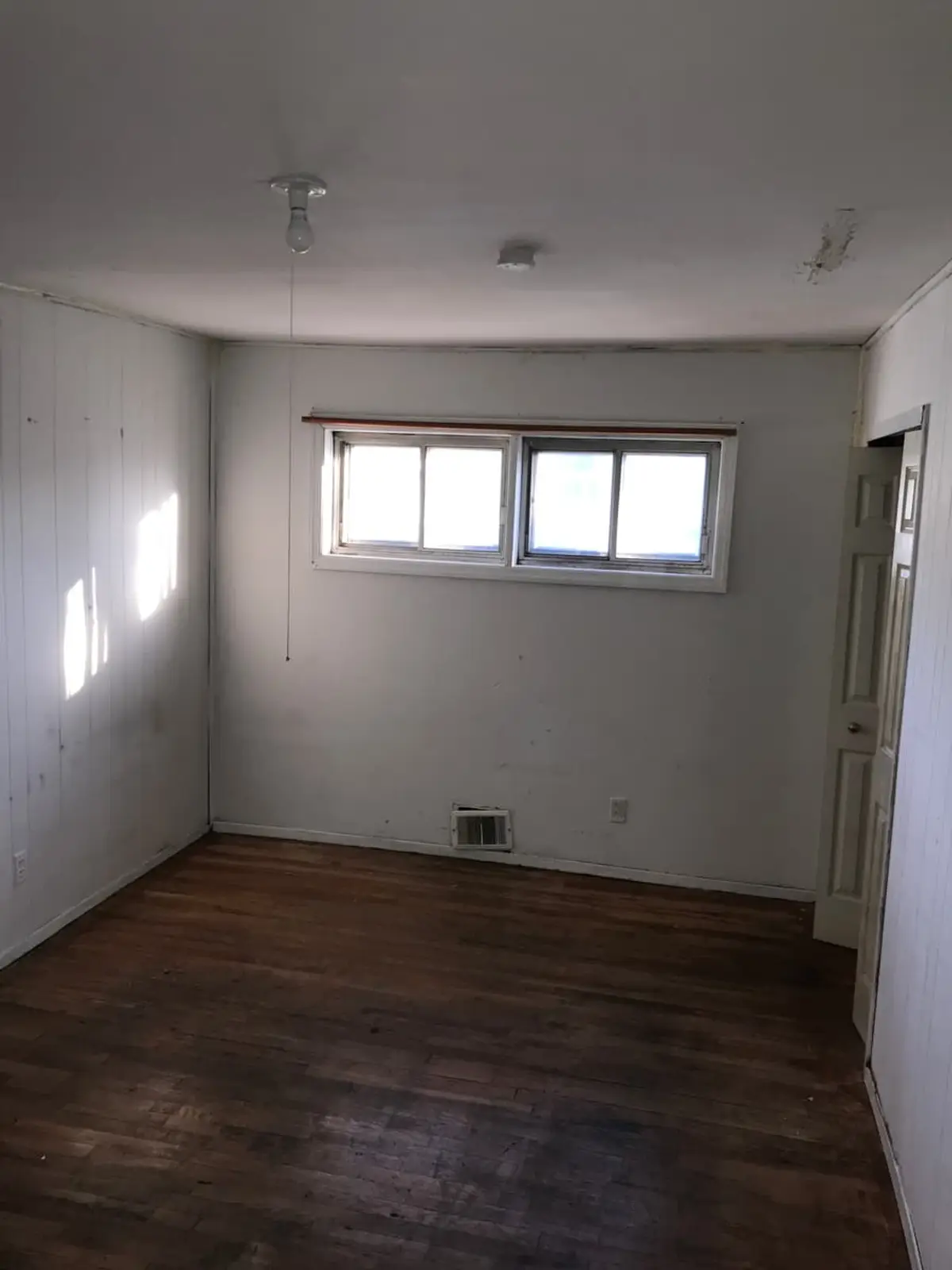 Trying to stop a foreclosure in Brentwood: empty white-paneled bedroom with a wood floor