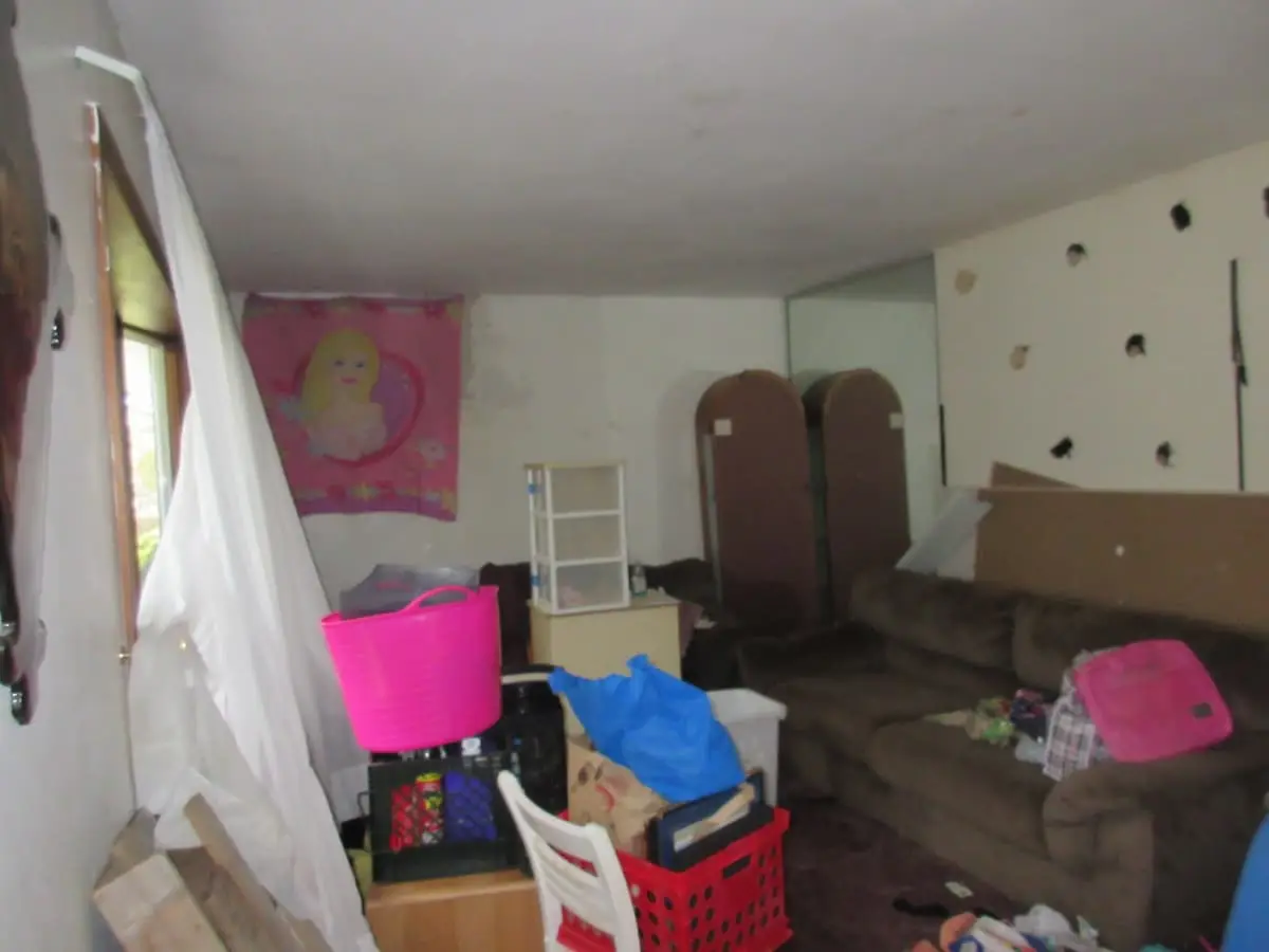 Selling a house with foundation problems in Brentwood: living room with damaged walls and belongings piled up
