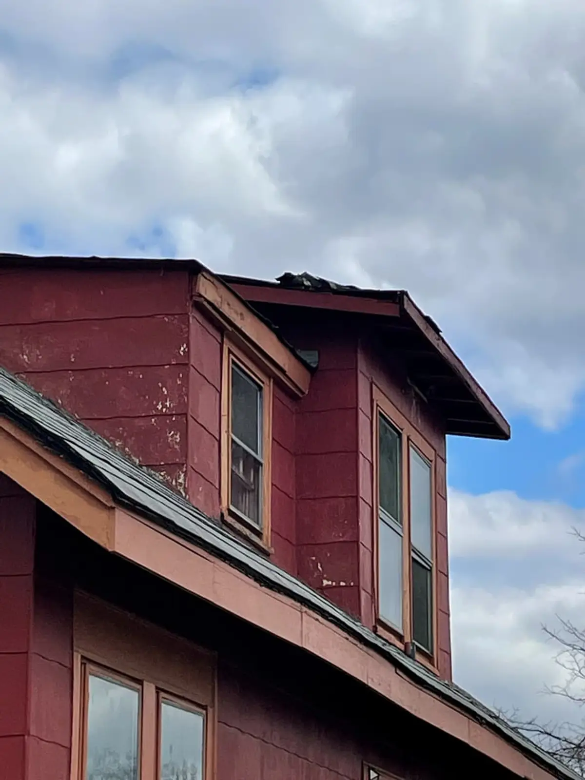 Selling a house after a life change in Brentwood: red-sided dormer with weathered trim against a cloudy sky