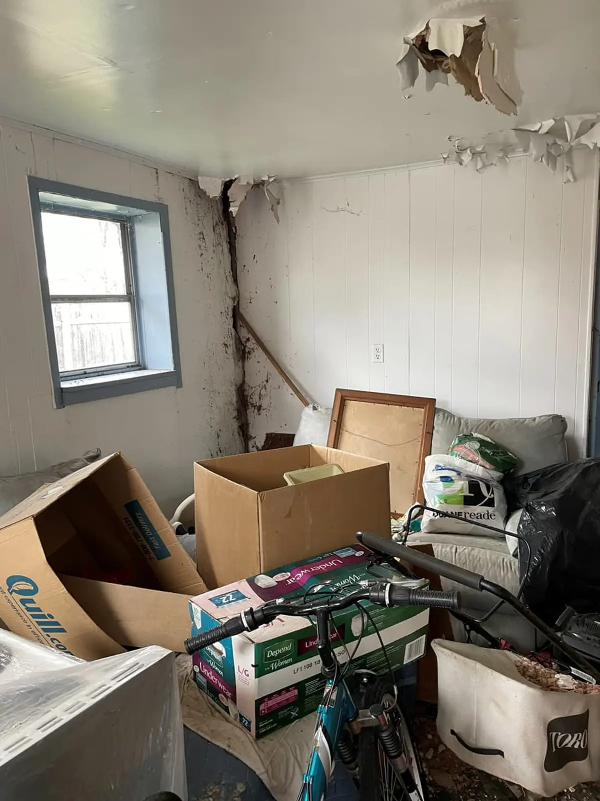 Selling a house as-is in Brentwood: room with a cracked wall and boxes stacked on the floor