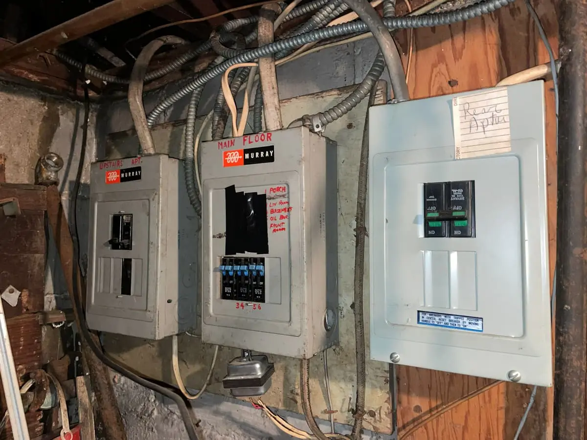 Selling a house with code violations in Brentwood: three old electrical panels on a basement wall