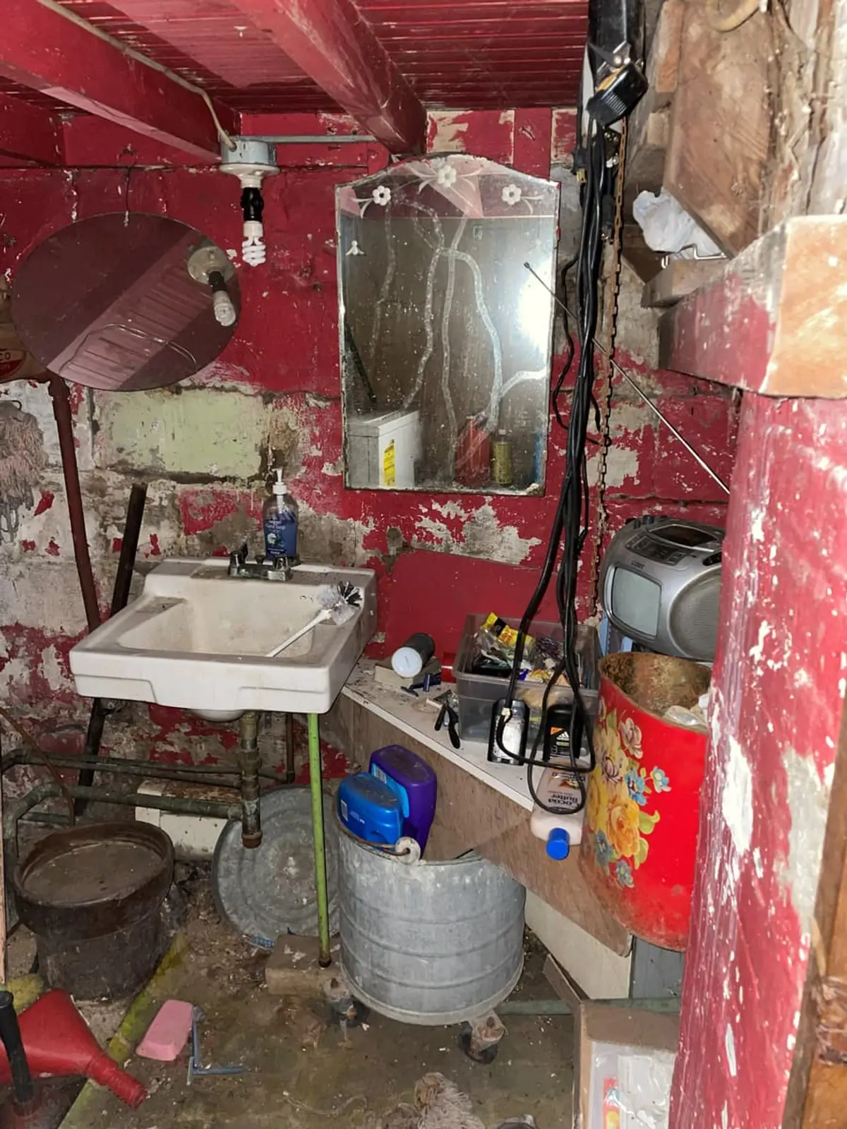 Selling a fire-damaged house in Brentwood: utility room with peeling red paint and a stained sink